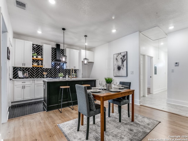 dining area featuring light hardwood / wood-style floors and a textured ceiling