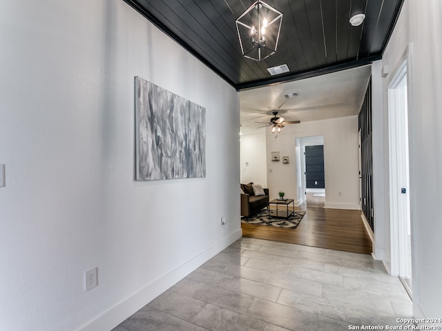 corridor with light hardwood / wood-style floors, a notable chandelier, ornamental molding, and wooden ceiling