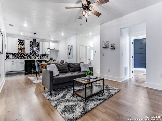 living room with light hardwood / wood-style floors and ceiling fan