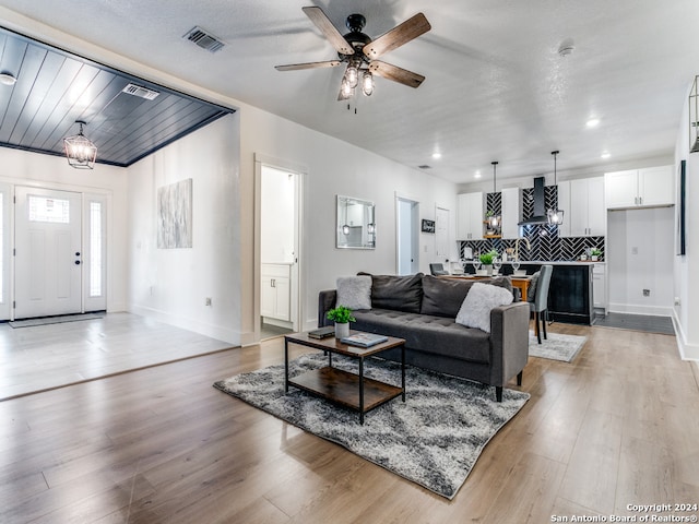 living room featuring light hardwood / wood-style flooring, a textured ceiling, and ceiling fan