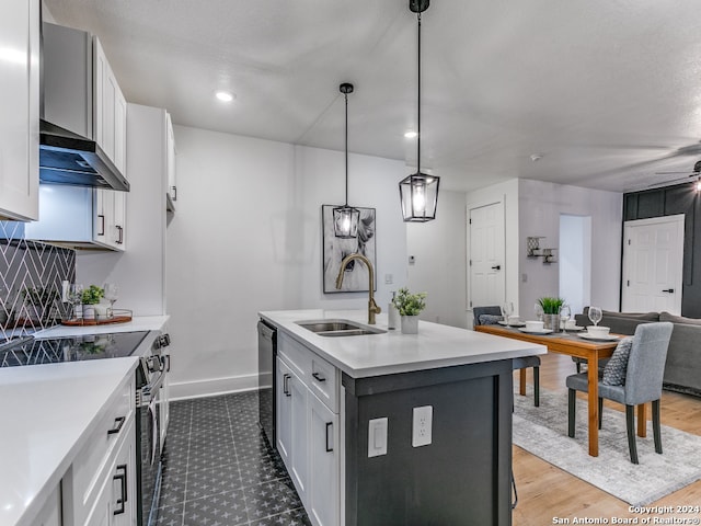 kitchen featuring sink, a kitchen island with sink, pendant lighting, and white cabinetry