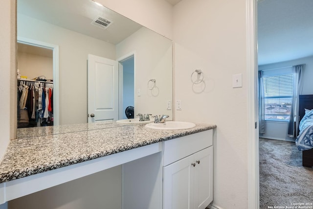 bathroom featuring visible vents, vanity, and a walk in closet