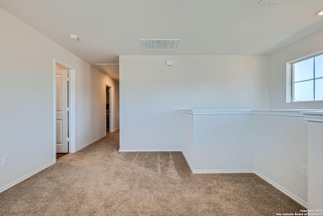 unfurnished room featuring attic access, visible vents, carpet flooring, and baseboards