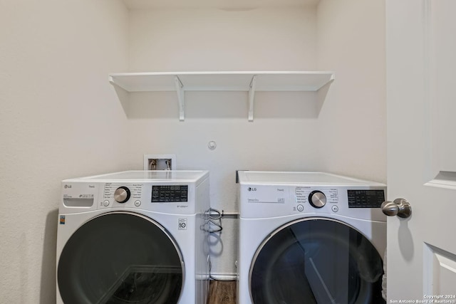 washroom with separate washer and dryer, wood finished floors, and laundry area