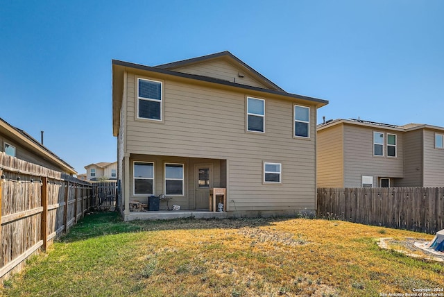 rear view of house featuring a patio area, a yard, and a fenced backyard