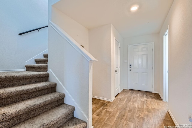 foyer entrance featuring stairs, baseboards, and light wood-type flooring