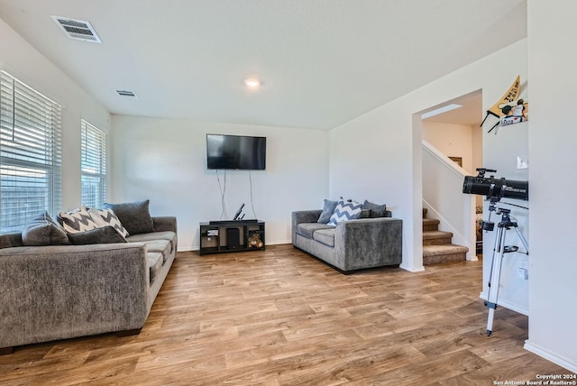 living area with stairway, visible vents, light wood finished floors, and baseboards