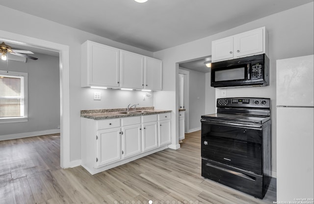 kitchen with light hardwood / wood-style floors, white cabinets, and black appliances