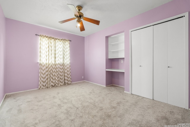 unfurnished bedroom featuring a closet, a textured ceiling, light colored carpet, and ceiling fan