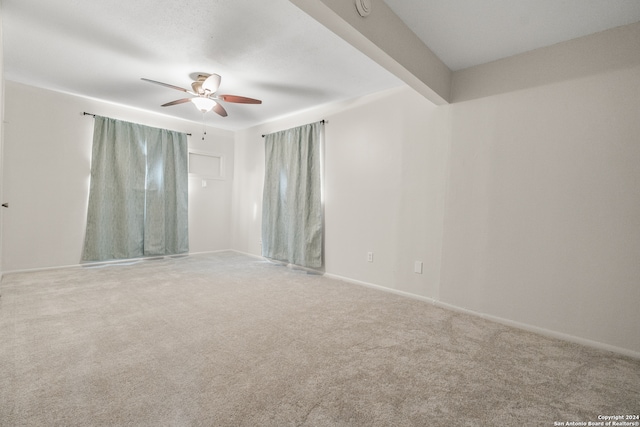 carpeted spare room featuring beamed ceiling and ceiling fan