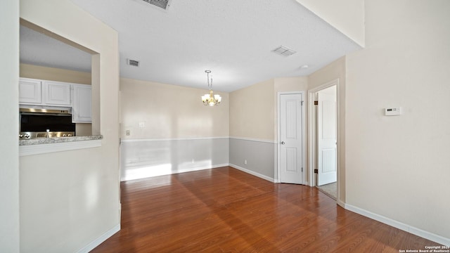 unfurnished dining area with hardwood / wood-style floors and an inviting chandelier