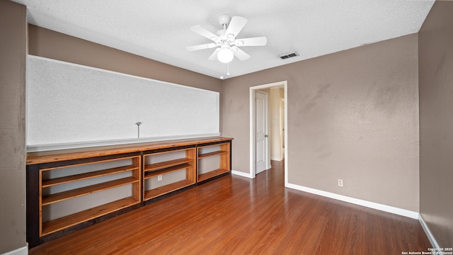 empty room featuring ceiling fan, dark hardwood / wood-style floors, and a textured ceiling