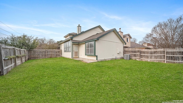 rear view of property with central AC unit and a yard