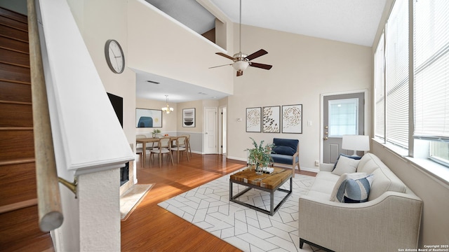 living room featuring ceiling fan with notable chandelier, light hardwood / wood-style floors, and high vaulted ceiling