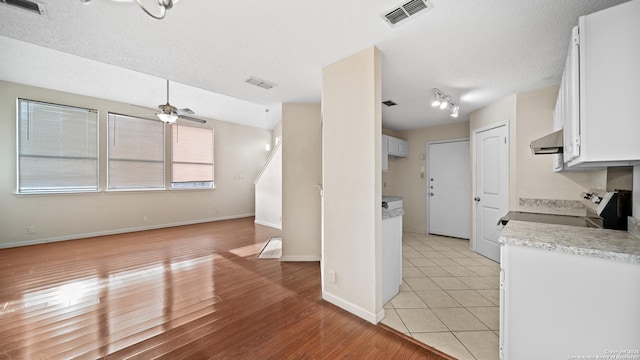 kitchen with ceiling fan, extractor fan, light tile patterned flooring, white cabinetry, and a textured ceiling