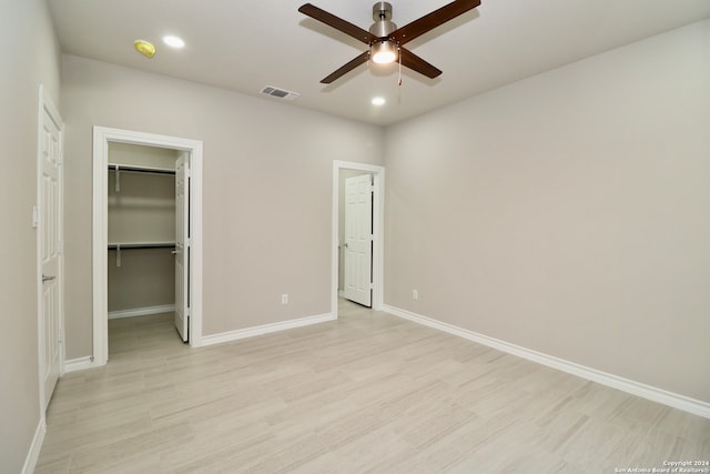 unfurnished bedroom with light hardwood / wood-style floors, a spacious closet, and ceiling fan