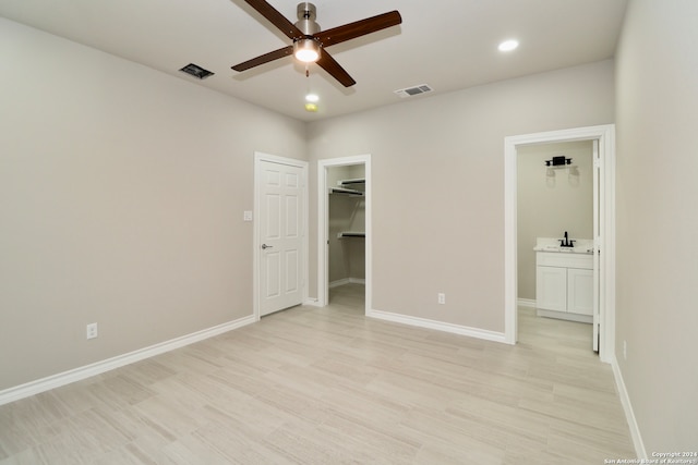 unfurnished bedroom with ensuite bathroom, sink, a walk in closet, light hardwood / wood-style floors, and ceiling fan