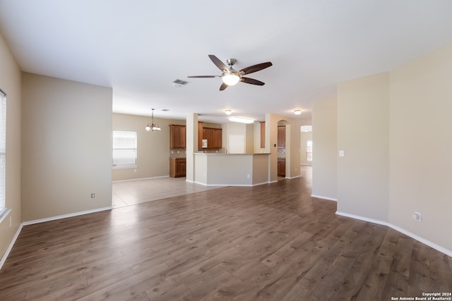 unfurnished living room with hardwood / wood-style floors and ceiling fan with notable chandelier