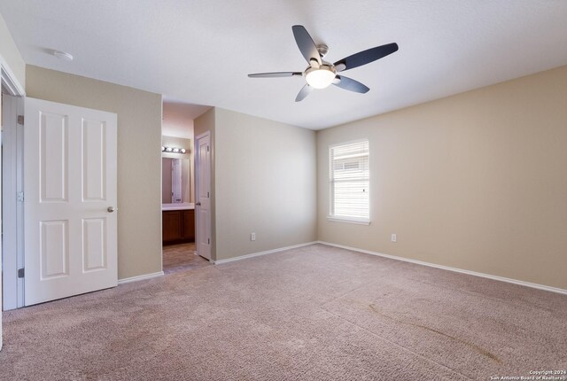 unfurnished bedroom featuring ceiling fan, carpet floors, ensuite bathroom, and baseboards