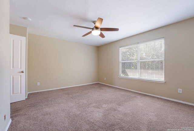 carpeted spare room with a ceiling fan and baseboards