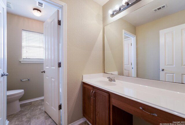 bathroom featuring baseboards, visible vents, toilet, and vanity