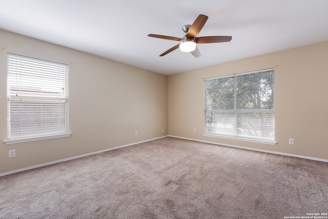 carpeted empty room with ceiling fan and a wealth of natural light