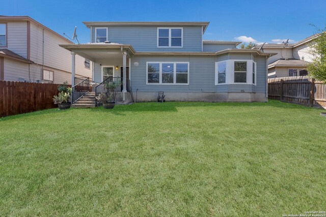 rear view of house with fence and a yard
