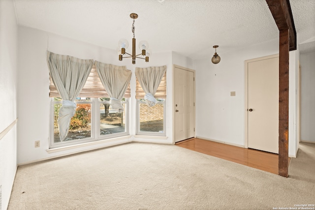 unfurnished dining area featuring a notable chandelier, a textured ceiling, and carpet floors