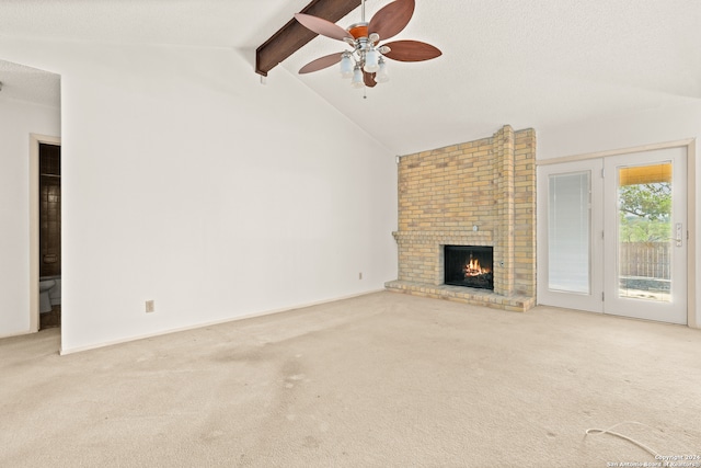 unfurnished living room with lofted ceiling with beams, light carpet, a fireplace, and ceiling fan