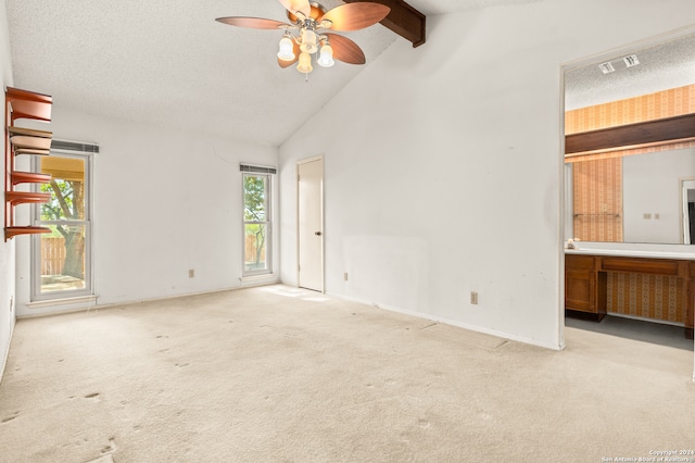 empty room with beamed ceiling, light carpet, a textured ceiling, and ceiling fan