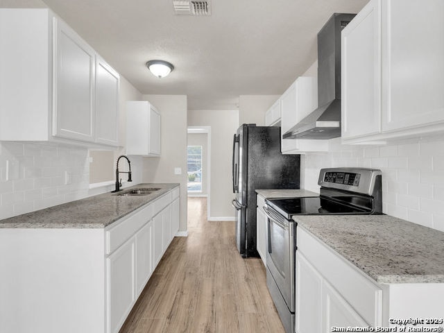 kitchen with wall chimney exhaust hood, white cabinetry, and stainless steel range with electric cooktop