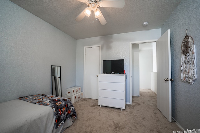 bedroom featuring ceiling fan, light carpet, and a textured ceiling