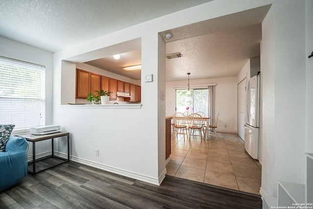 kitchen with a textured ceiling, dark hardwood / wood-style flooring, white refrigerator, and hanging light fixtures