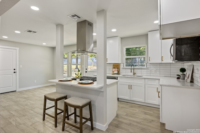 kitchen featuring a center island, sink, light wood-type flooring, and white cabinets