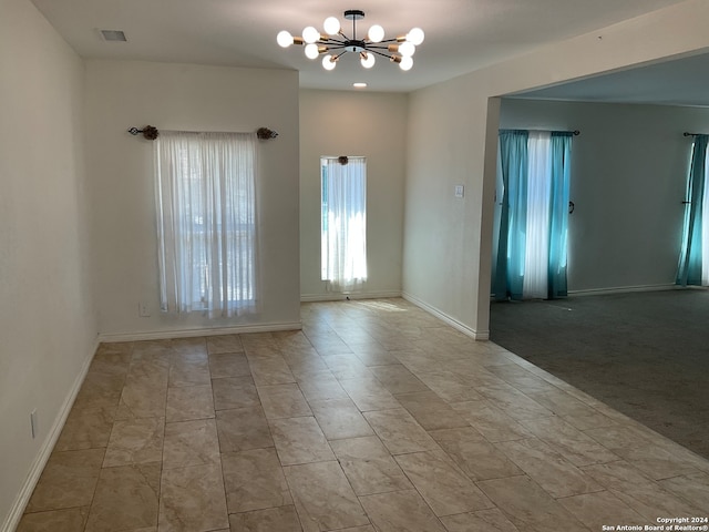 carpeted spare room featuring a notable chandelier