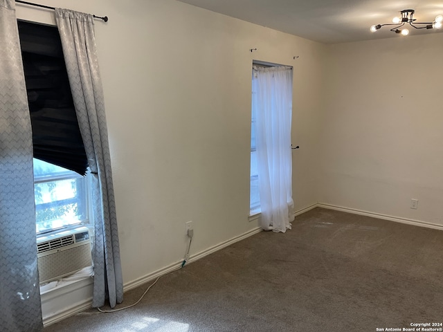 carpeted spare room with a chandelier