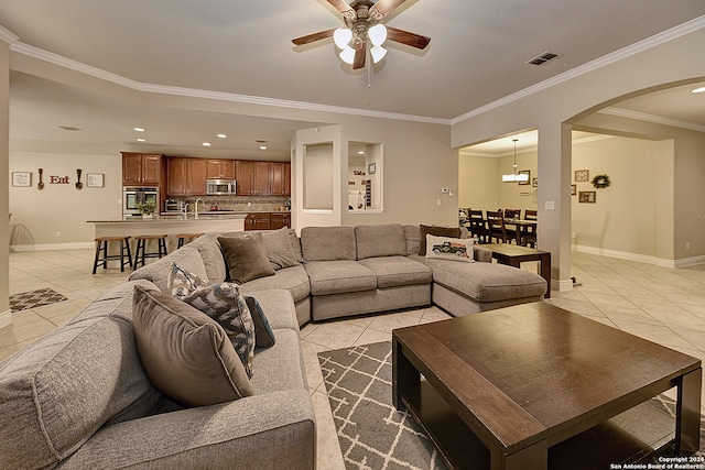 tiled living room featuring ornamental molding and ceiling fan