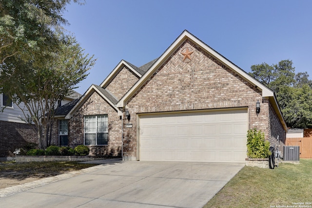 view of front of house featuring central air condition unit, a front yard, and a garage