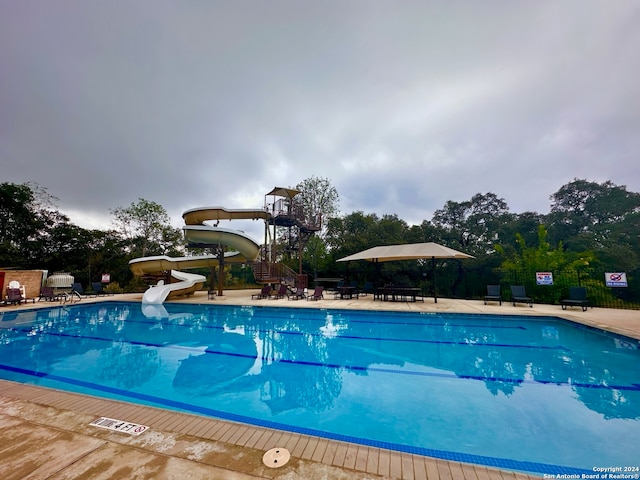 view of swimming pool featuring a water slide and a patio area