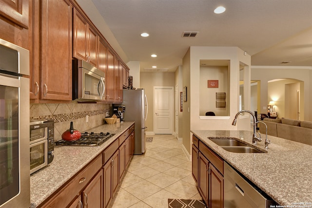 kitchen featuring sink, light stone countertops, stainless steel appliances, and backsplash