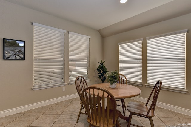 tiled dining space with lofted ceiling