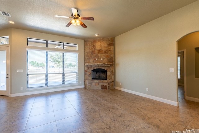 unfurnished living room with ceiling fan, a textured ceiling, and a fireplace