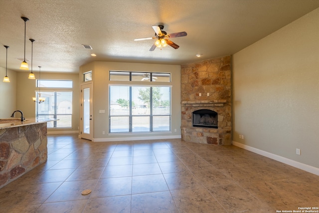 living room featuring tile patterned floors, a fireplace, a textured ceiling, and ceiling fan with notable chandelier