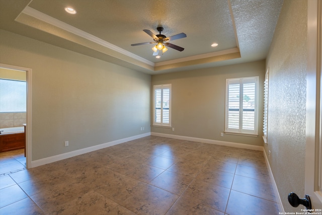 tiled spare room featuring crown molding, a textured ceiling, a tray ceiling, and ceiling fan