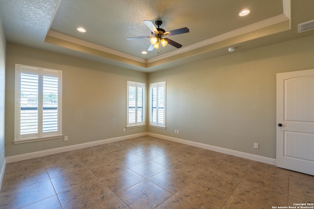 empty room with ceiling fan, a textured ceiling, and a tray ceiling