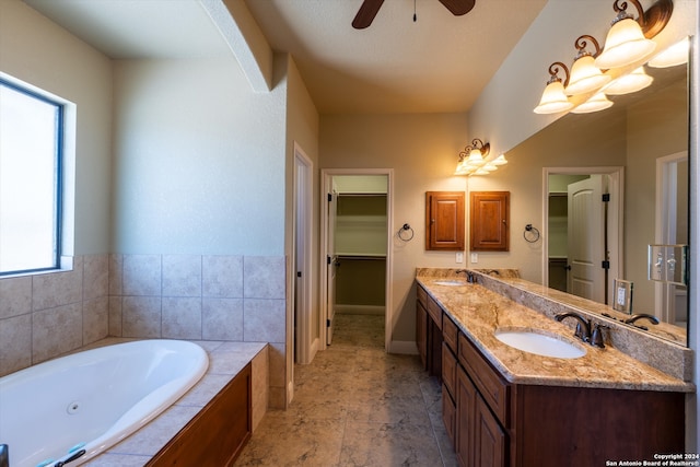 bathroom featuring vanity, a textured ceiling, tiled tub, and ceiling fan