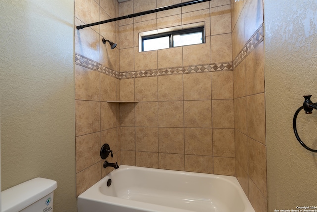 bathroom with toilet and tiled shower / bath