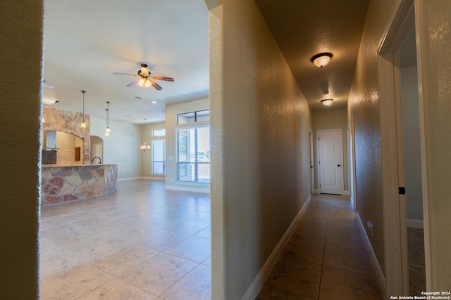 hallway with a textured ceiling and light tile patterned floors