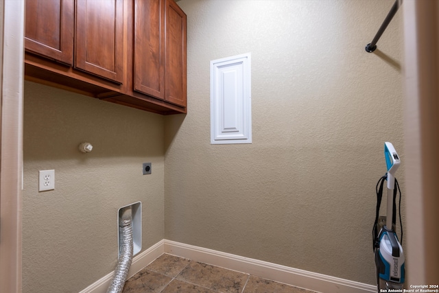 laundry room featuring hookup for an electric dryer, light tile patterned floors, and cabinets