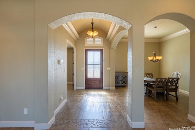 entrance foyer with an inviting chandelier, ornamental molding, and vaulted ceiling